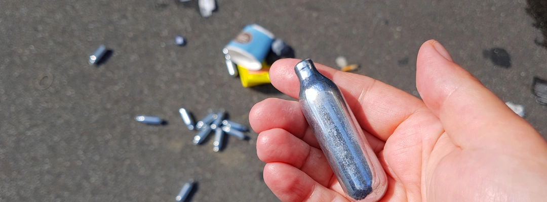 Image of a man's hand holding a silver tone nitrous oxide cylinder - How Long Does Nitrous Oxide Last in Your System - Purpose Healing Center