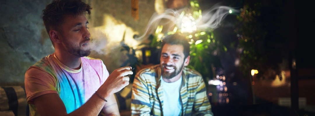 Image of a man smoking cannabis while another man is in the background, showing potential secondhand smoke exposure