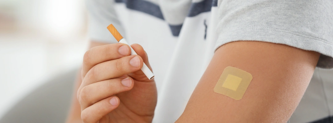 Image of man holding a cigarette and wearing a nicotine patch