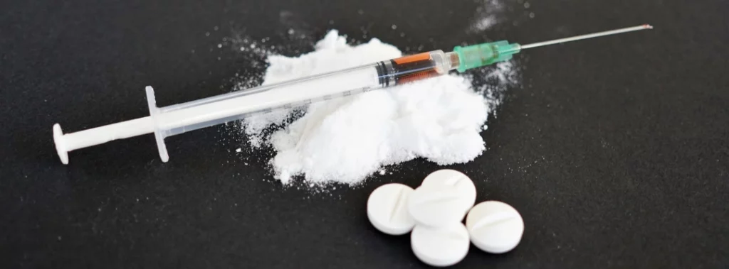 Image of meth powder, a syringe, and pills on a table - What Is A Goofball - Purpose Healing Center