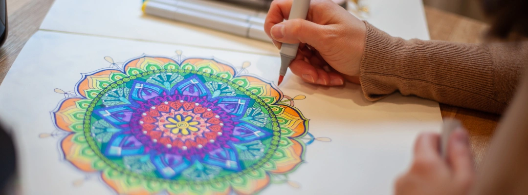 Image of a man's hands coloring a mandala as calming art therapy in recovery