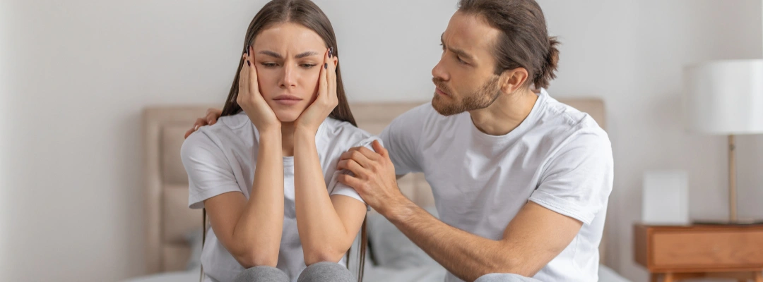 Image of a woman with her hands on her face, setting personal boundaries in a relationship during al conversation with the man next to her